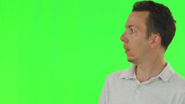 Beyaz polo tişörtlü adam kafasını aniden yana çeviriyor. Yeşil ekranın önünde şaşırmış veya şok olmuş yüz ifadeleri var. Sürpriz, tepki ya da komedi uyarısı için birebir..