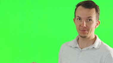 Bir adam, yeşil bir ekranın önünde gülümserken ve neşeyle hareket ederken bir yandan da işaret parmağıyla hareket eder. görsel efektler ve medya üretimi için uygun