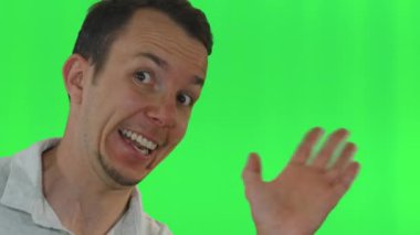 Yetişkin erkek yandan bakıyor ve coşkuyla el sallıyor ve yeşil ekranda geniş bir gülümseme sergiliyor. Hoş geldin ya da komik içerik için enerjik ve neşeli ifade ideal.