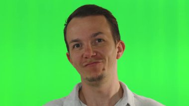 Sıradan giyinmiş bir adam yeşil bir ekranın önünde hareketsiz dururken kendine güvenen ve biraz da eğlenen bir yüz ifadesi sergiler. Reaksiyon veya iletişim düzenlemeleri için kullanışlı.
