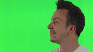 Beyaz kapüşonlu bir adamın yeşil krom anahtar arka planına bakıp kameraya gülümsemesi video projelerinde veya içerik oluşturmada ideal..
