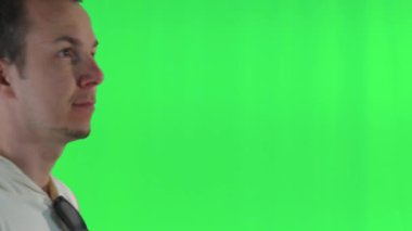 Sıradan giyinmiş bir adam yandan yaklaşır ve kameranın yanında duran birini fark eder. Neşe ve coşkuyu parlak gülümsemeler ve kahkahalarla ifade eder canlı yeşil ekran düzenine karşı.