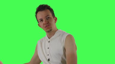 Beyaz kolsuz kapüşonlu bir adam abartılı, esprili pozlar verir. Yeşil bir ekranın önünde, mizahi içerik, mim ya da anlamlı kurgular için uygun.