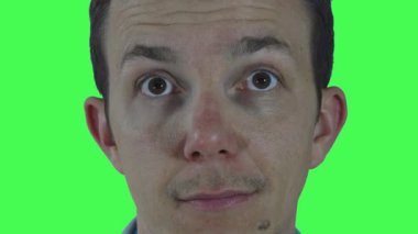 Genç bir adamın yumuşak, nazik bir gülümsemeyle kameraya baktığı yakın çekim video sahnesi. Yaratıcı ve ticari kullanım için kolay kompozitasyon sağlamak amacıyla yeşil ekran arka planına karşı çekilen.
