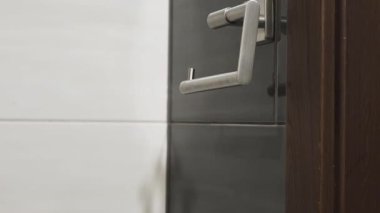 Tuvalet kağıdı rulosunu modern bir krom sapına yerleştiren ve ayarlayan kişinin yakın çekim sekansı günlük hijyen görevini gösteriyor..