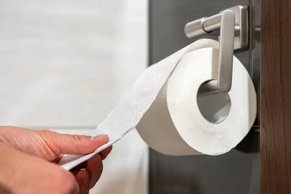 Temizlik, temizlik ve tuvalet kullanımını temsil eden, seramik duvardaki tuvalet kağıtlarının elle açılması.