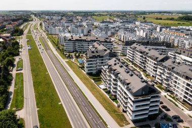 Apartman kompleksleri ve otoyolları ayıran yeşil kuşaklı şehir yolu manzarası.