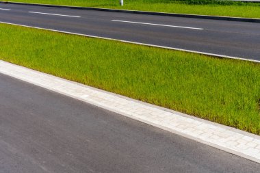 Güneşli bir günde yeşil çimen medyan şeritli modern asfalt yolu, kentsel altyapı ve peyzaj