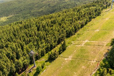Spruce Ormanı 'ndan geçen teleferik hattı ve yaz günü dağ bölgesindeki açıklıklar.