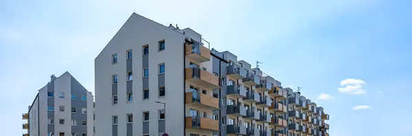 Mavi gökyüzü altında birden fazla balkonu olan modern yerleşim binaları, kentsel konut geliştirme ve mimari sergileniyor