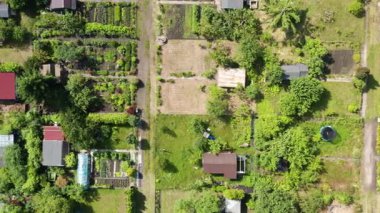 Yapılandırılmış yolları, ekili bölümleri, seraları ve zengin bir banliyö bölgesindeki döküntüleri olan yaz tahsis bahçelerinin tepeden tırnağa insansız hava aracı görüntüleri.