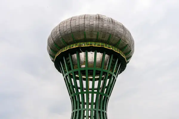 Bulutlu gökyüzü, mimari yapı ve kamu hizmetlerine karşı olağandışı yeşil ve gri fütüristik su kulesinin yakın çekimi