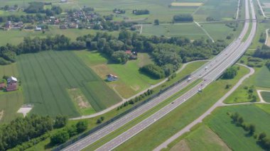 Bu hava aracı klibi, yeşil tarlaları ve yakındaki köy kümelerini geçen çok şeritli bir otoyolu takip ediyor. Görüntülerde ulaşım altyapı düzeni, trafik hareket modelleri ve arazi kullanımı yapılandırması vurgulanıyor.