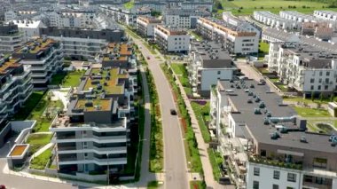 Bu hava aracı görüntülerinde yeşil çatıları, manzaralı caddeleri ve yaz güneşinin altında ağaçlarla kaplı kaldırımları olan banliyö apartmanlarının üzerinde mimari tasarım ve şehir planlaması sergilenen pürüzsüz bir uçuş görülüyor..