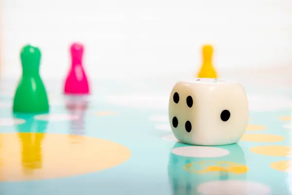 Zar ve renkli plastik piyonlar oyun yüzeyinde eğlence aktivitesini ve kapalı alanda eğlenceyi vurguluyor