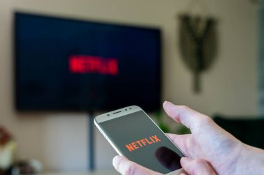 Netflix uygulaması açık olan akıllı telefon kullanan kişi Netflix logosunu görüntülerken