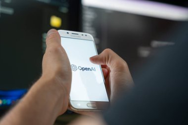 Ekranda OpenAI logosu olan akıllı telefon kullanan kişi, yapay zeka araştırma ve teknoloji şirketi