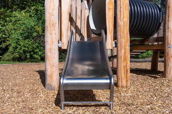 Tahta parktaki paslanmaz kaydırak oyunu, çocuklar için güvenli oyun alanı ve eğlence.