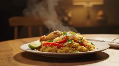 Balık ve sebzeli enfes bir kuskus tabağı loş ışıkta, ahşap bir masada oturur.