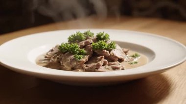 Lezzetli bir tabak maydanozlu stroganof, ahşap bir masada buharda pişiyor. Yemek hazır..