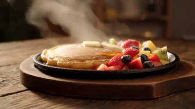 Ahşap bir yüzey masasında siyah bir tabakta tereyağı ve meyveli krep yakın çekim.