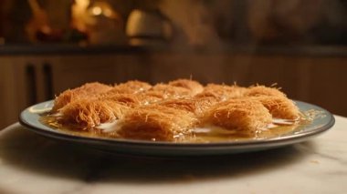 Sıcak bir mutfak ortamında şerbetli bir tabakta kanafeh 'in yakın çekimi. Tatlı nefis.