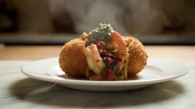 Beyaz bir tabakta servis edilen yeşil soslu ve karidesle dolu lezzetli bir ekmek kasesi..