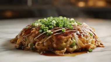 Sos ve yeşil soğanlı okonomiyaki sergilenen yakın çekim..