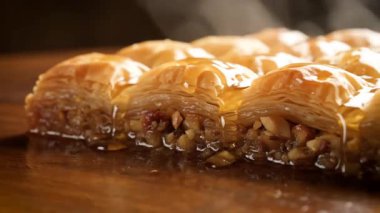 Yakın plan bir baklava görüntüsü, loş ışıkta hamur işi, fındık ve şurup katmanlarını gösterir.