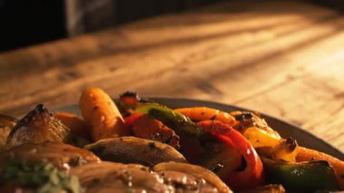 Ahşap bir masanın üstünde havuç, biber ve soğan dolu bir tabakta yakın plan sebzeler..