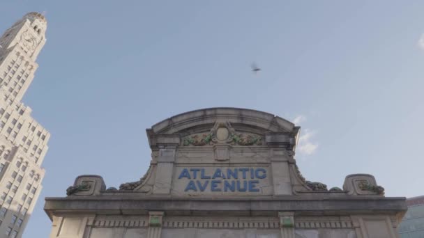 ブルックリンのアトランティック アベニュー上空を飛ぶピジョンズのハンドヘルドショット アトランティックターミナル外の晴れた朝に撮影 背景にあるウィリアムズバーグ貯蓄銀行 — ストック動画