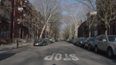 Sakin bir Brooklyn caddesinin el kamerasıyla çekilmiş fotoğrafı. Bir bahar öğleden sonra 4K 'da çekilmiş..