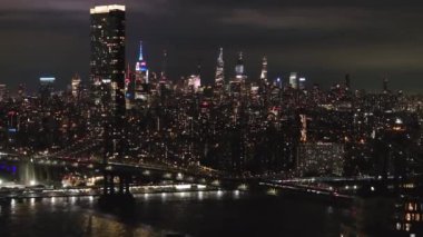 Geceleri New York şehrinin gökyüzü manzarası. Çerçevede Manhattan Köprüsü ve Empire State Binası var..