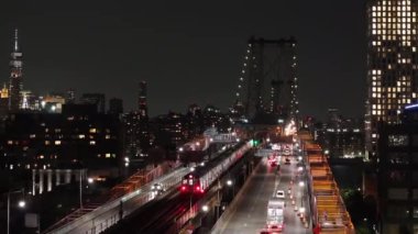 Williamsburg Köprüsü 'nü geçen metronun hava görüntüsü. Brooklyn, New York 'ta bir yaz gecesi çekilmiş..