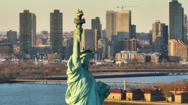 Gün batımında Özgürlük Heykeli 'nin havadan görünüşü. Arka planda New York şehrinin silueti var..