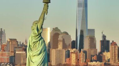 Gün batımında Özgürlük Heykeli 'nin havadan görünüşü. Arka planda New York şehrinin silueti var..