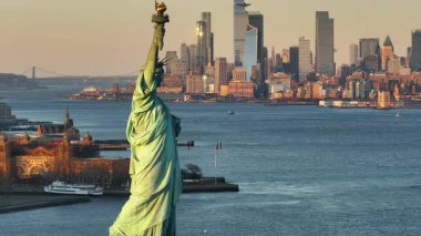 Gün batımında Özgürlük Heykeli 'nin havadan görünüşü. Arka planda New York şehrinin silueti var..