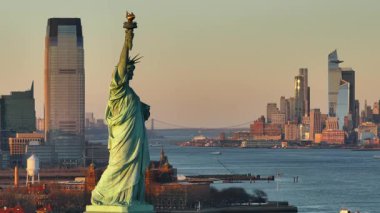 Gün batımında Özgürlük Heykeli 'nin havadan görünüşü. Arka planda New York şehrinin silueti var..