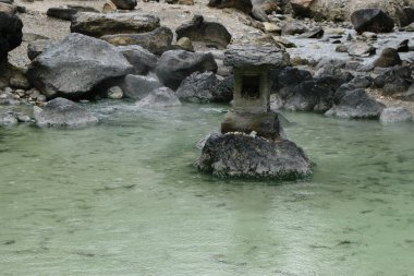 Japon onsen suyuyla çevrili taşın üzerindeki bir fener..