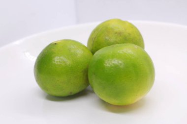bir tabakta üç yeşil ekşi limon