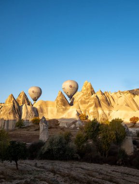 Kapadokya-Goreme üzerinde 20 Ekim 2022 'de hava balonları. Canlı bir ışık ve renk patlaması ve garip kaya oluşumunun üzerinde bir hava balonu uçurma heyecanı..