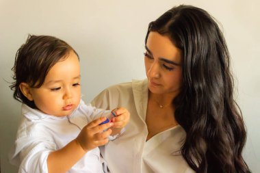 Latin anne, bir oyuncakla oynarken bebeğine sevgiyle bakar.