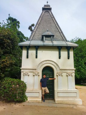 Latin man in front of an ancient pavilion in the Quinta de la Fuente del Berro park in Madrid - Spain clipart