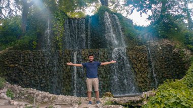Young Latin man at a waterfall in the Parque de la Quinta de la Fuente del Berro in Madrid Spain - Europe clipart