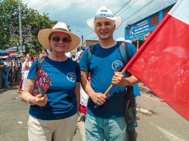 Neiva, Huila, Kolombiya - 30 Haziran 2024 - Bir geçit töreninde kameraya bakarken ellerinde Polonya bayrağı tutan iki Avrupalı turist