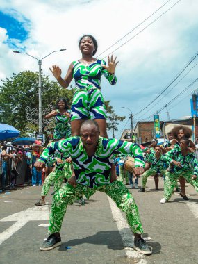 Neiva, Huila, Kolombiya - 30 Haziran 2024 - Genç Latin bir kadın San Pedro Festivali 'nde dans ederken siyah bir Latin erkeğin üstünde