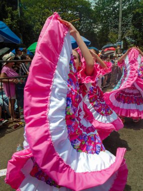 Neiva, Huila, Colombia - June 30, 2024 - Young white Latina woman in pink dress performing a dance in a parade clipart