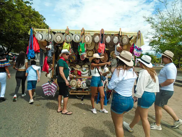 Neiva, Huila, Kolombiya - 30 Haziran 2024 - San Pedro 'da geleneksel şapkalar satan bir büfenin önünden geçen turistler