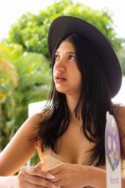 Siyah şapkalı, yukarı bakan Latin bir kadının endişeli ifadesi.