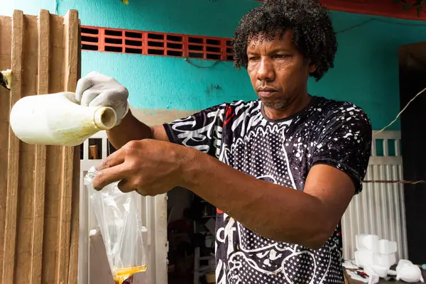 stock image Dark-skinned Latino man with curly hair pouring oil into a transparent bag